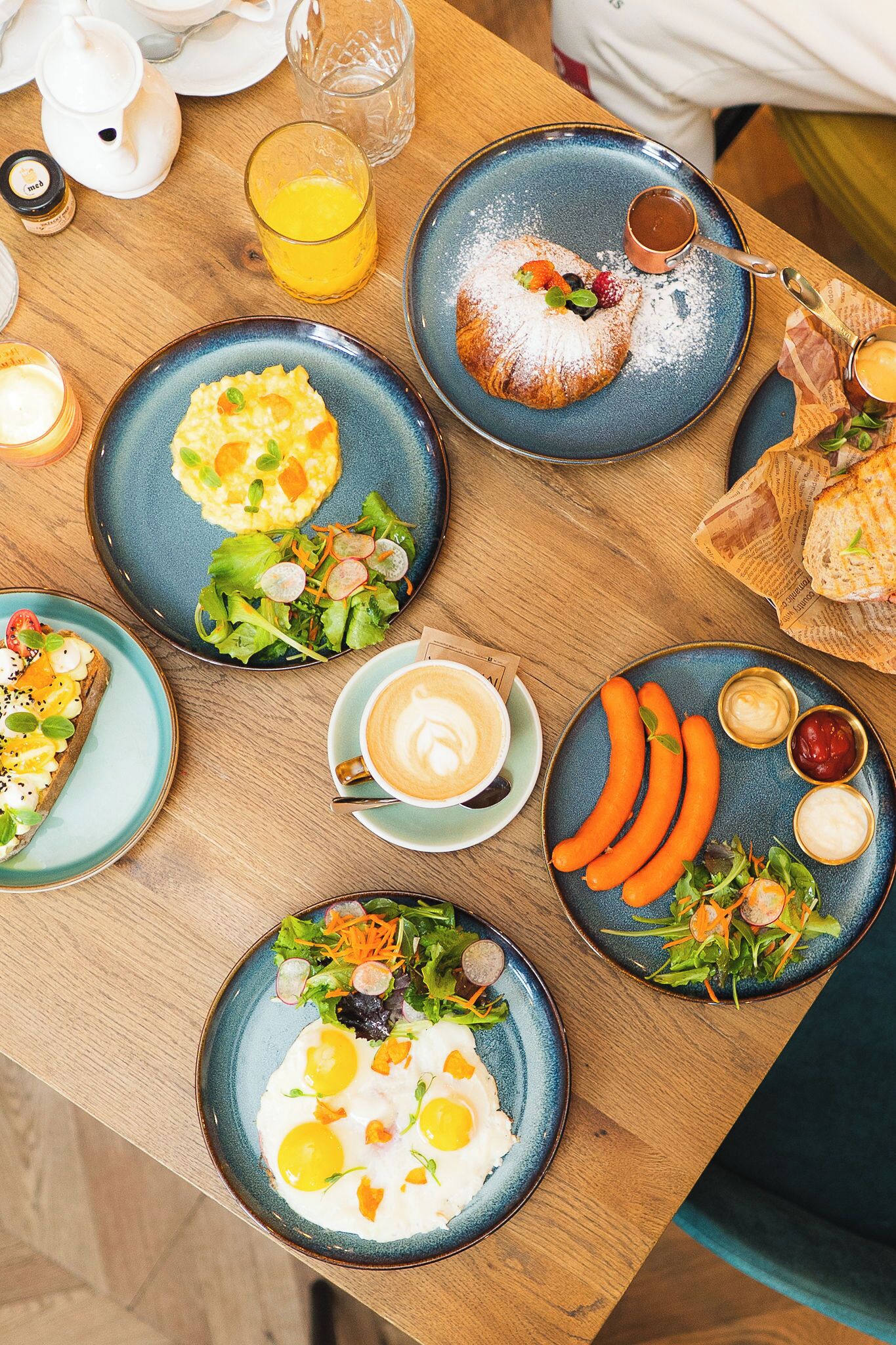 A table with various dishes, a cup of coffee, and a glass of orange juice.
