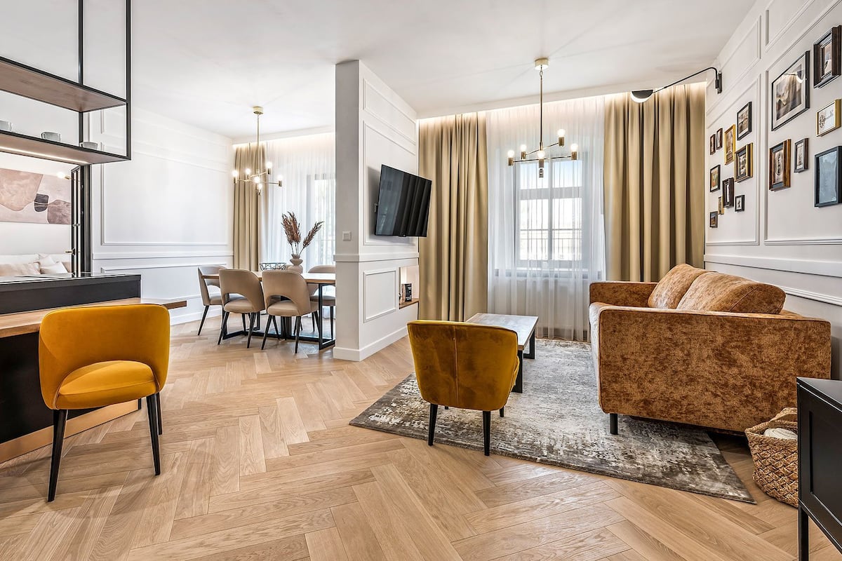 Una sala de estar moderna con un sofá, sillas, un televisor y un comedor con una mesa y sillas.