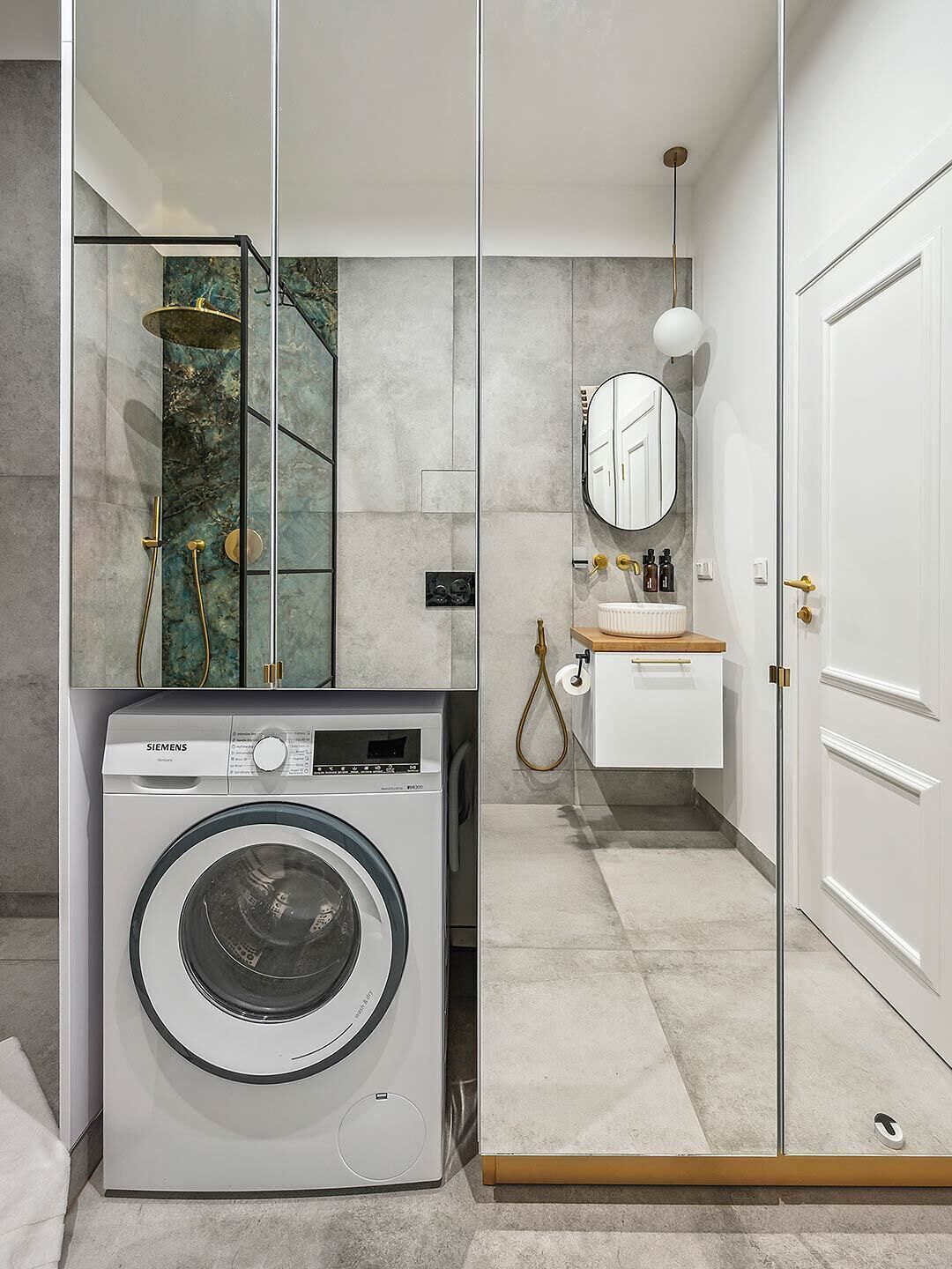 A modern bathroom with a washing machine, a glass shower enclosure, a sink with a mirror, and a toilet.