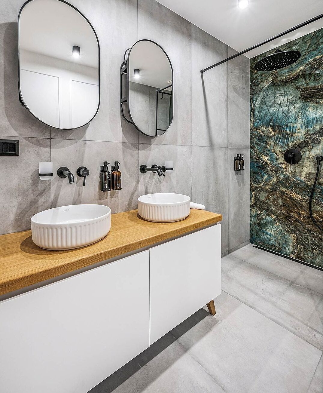 Une salle de bain moderne avec deux vasques blanches, un plan de travail en bois et un grand miroir.