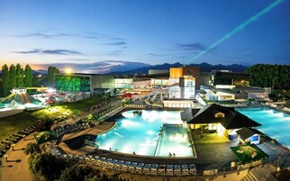 Un resort con una amplia piscina, varias edificaciones y montañas al fondo.