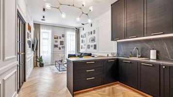 A modern kitchen with dark cabinetry, a marble countertop, and a pendant light fixture.
