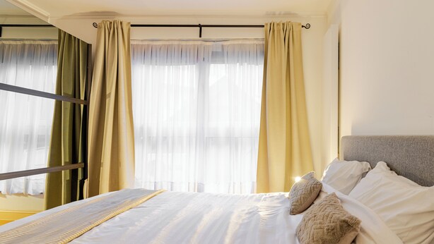 Une chambre d’hôtel avec un lit, des rideaux et une fenêtre.