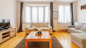 Un salon moderne avec deux canapés, une table basse et un téléviseur posé sur un meuble en bois.