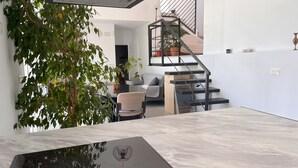 A modern living space with a dining table, a sofa, and a staircase with a railing.
