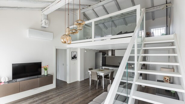 A modern loft with a dining area, kitchen, and a staircase leading to an upper level. - Casa del Borgo by Wonderful Italy (Bologna)
