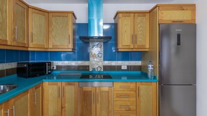 Una cocina con armarios de madera, refrigerador de acero inoxidable, microondas y encimera azul.