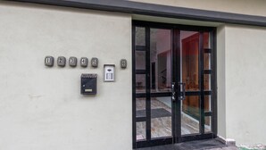 Entrada de un edificio con buzones numerados y una puerta.