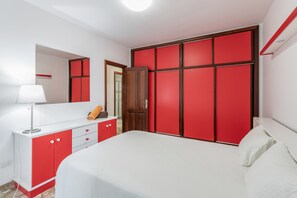 Une chambre à coucher comprenant un lit, une commode, un miroir et une armoire.