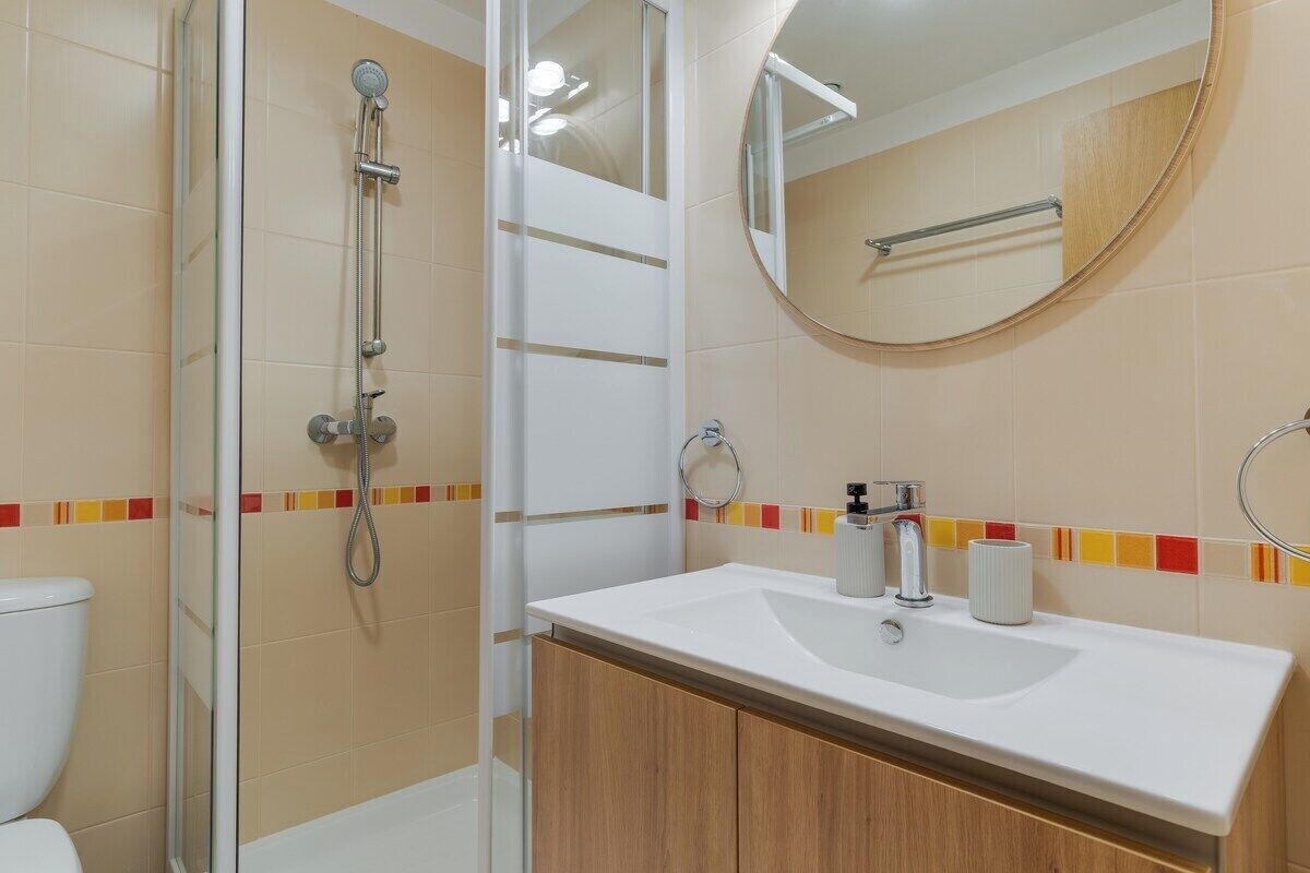 A bathroom with a shower, toilet, sink, and mirror.