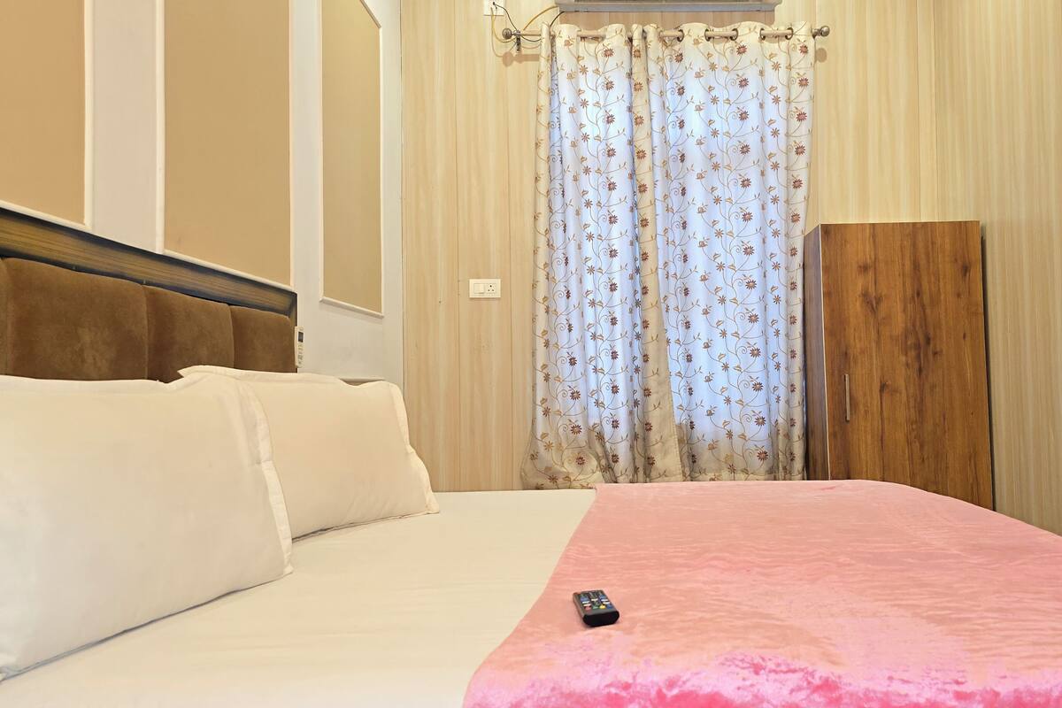 A hotel room with a bed, a wooden wardrobe, and a curtain with a floral pattern.