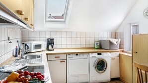 Eine kompakte Küche mit Waschmaschine, Mikrowelle und Spüle.
