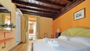 A hotel room with a bed, a mirror, a window with curtains, and a wooden ceiling.