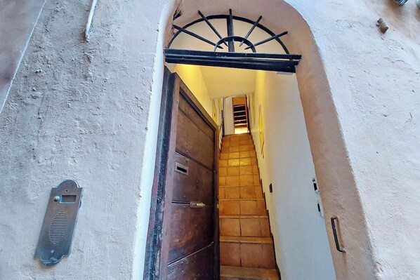 A narrow stairway leading to a door with a metal security device.