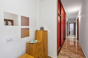 Un couloir avec une armoire en bois, un mur rouge et un sol carrelé.