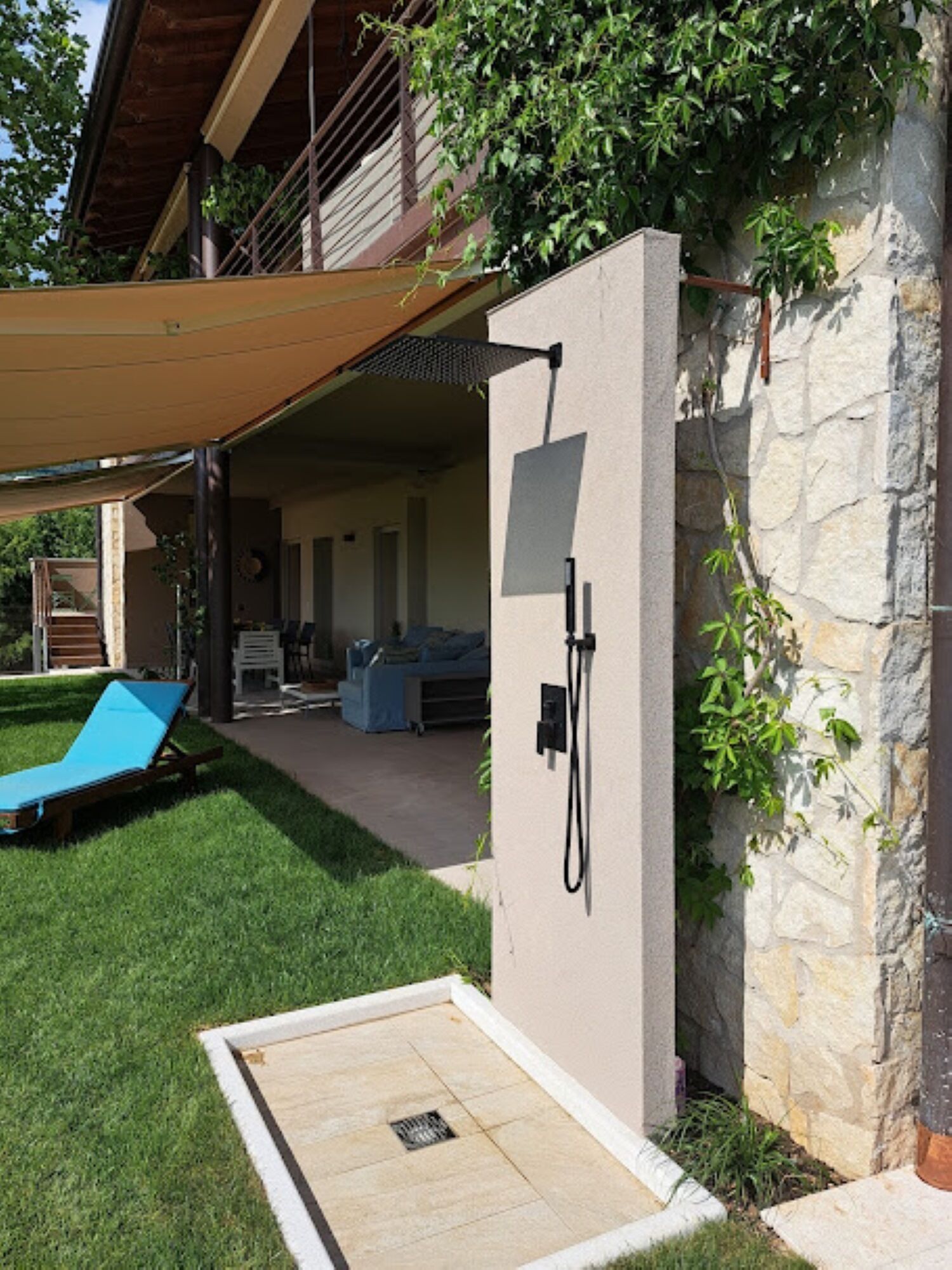 Un espace extérieur abrité comprenant une piscine, des chaises longues et un mur en pierre.