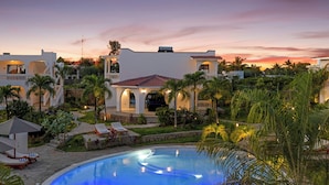 Un resort con piscina, sillas de descanso y palmeras.