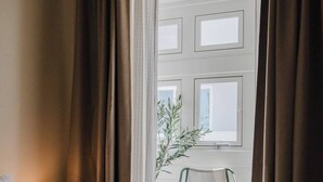 A hotel room with a bed, a chair, a lamp, and a view of the outside.