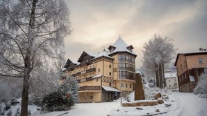 A snow-covered building with a tower, a paved driveway, and snow-laden trees. - Santa Christina (Świeradów-Zdrój)