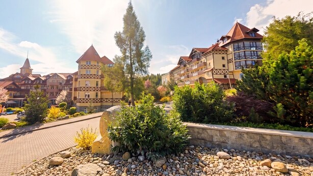 A hotel with traditional architecture, multiple balconies, and a stone pathway. - Santa Christina (Świeradów-Zdrój)