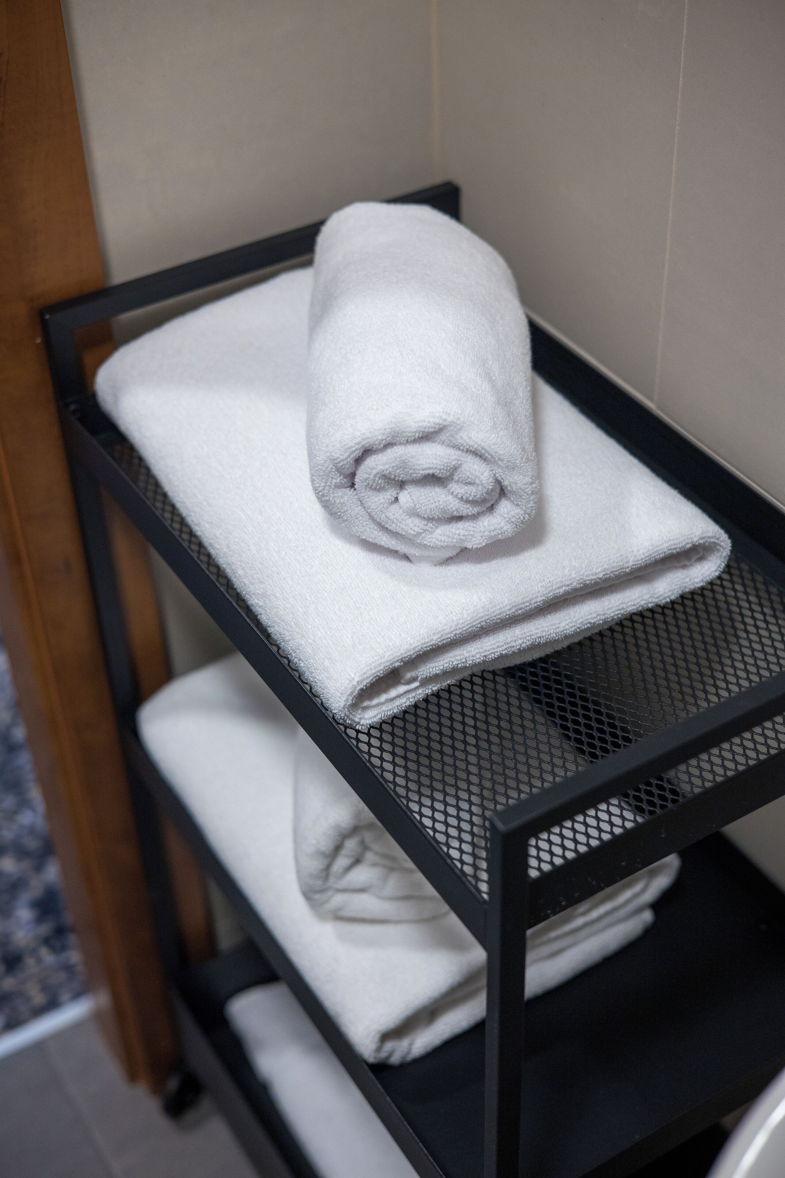 A black metal rack with two white towels folded and stacked.