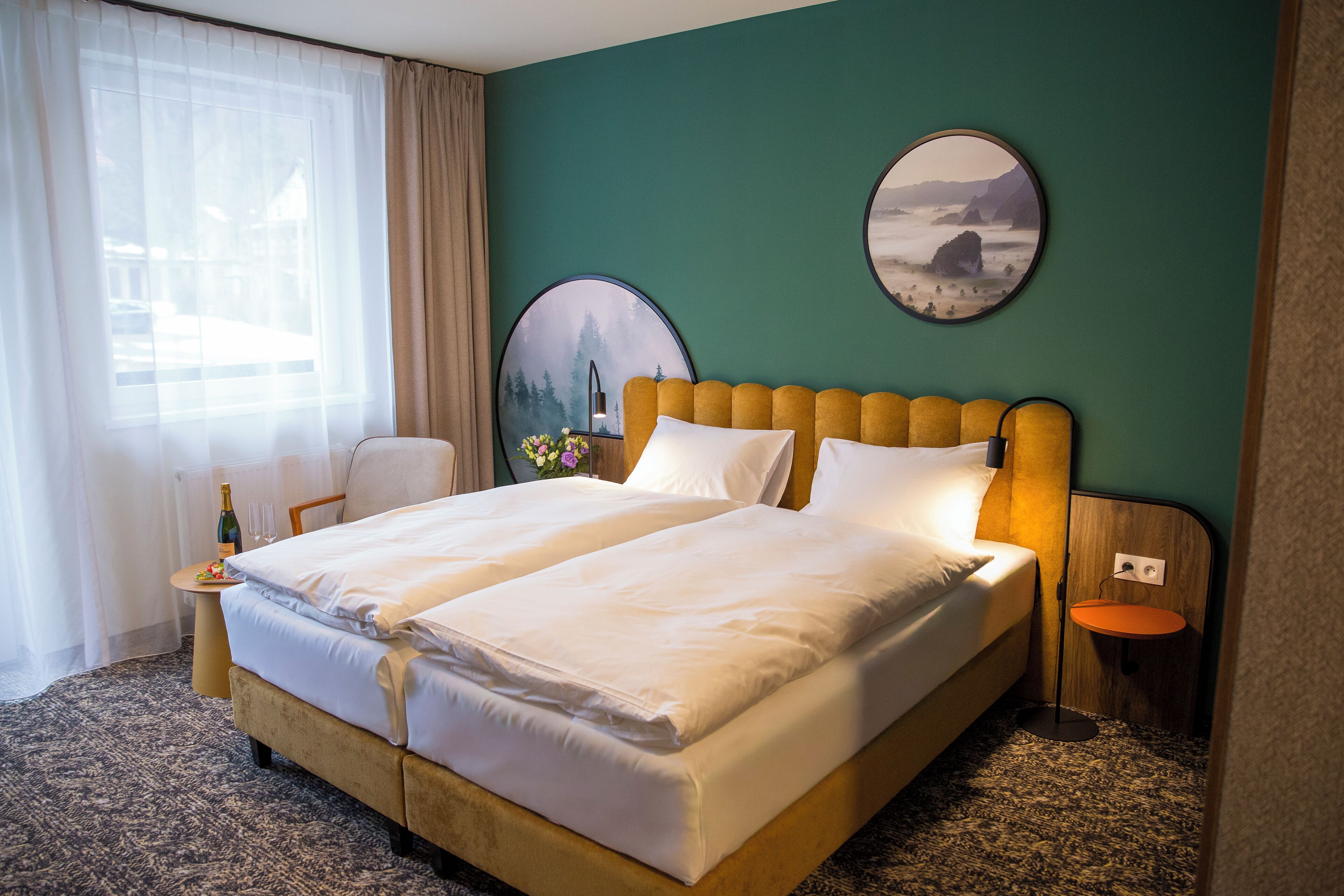 A double bed with a wooden headboard, a bedside table with a bottle and glasses, and two wall-mounted round mirrors.