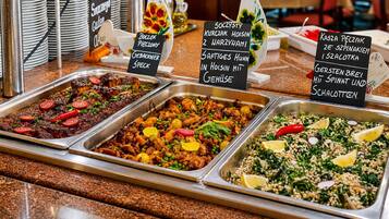 A buffet with various dishes, including meat, vegetables, and salads, with labels in a foreign language.
