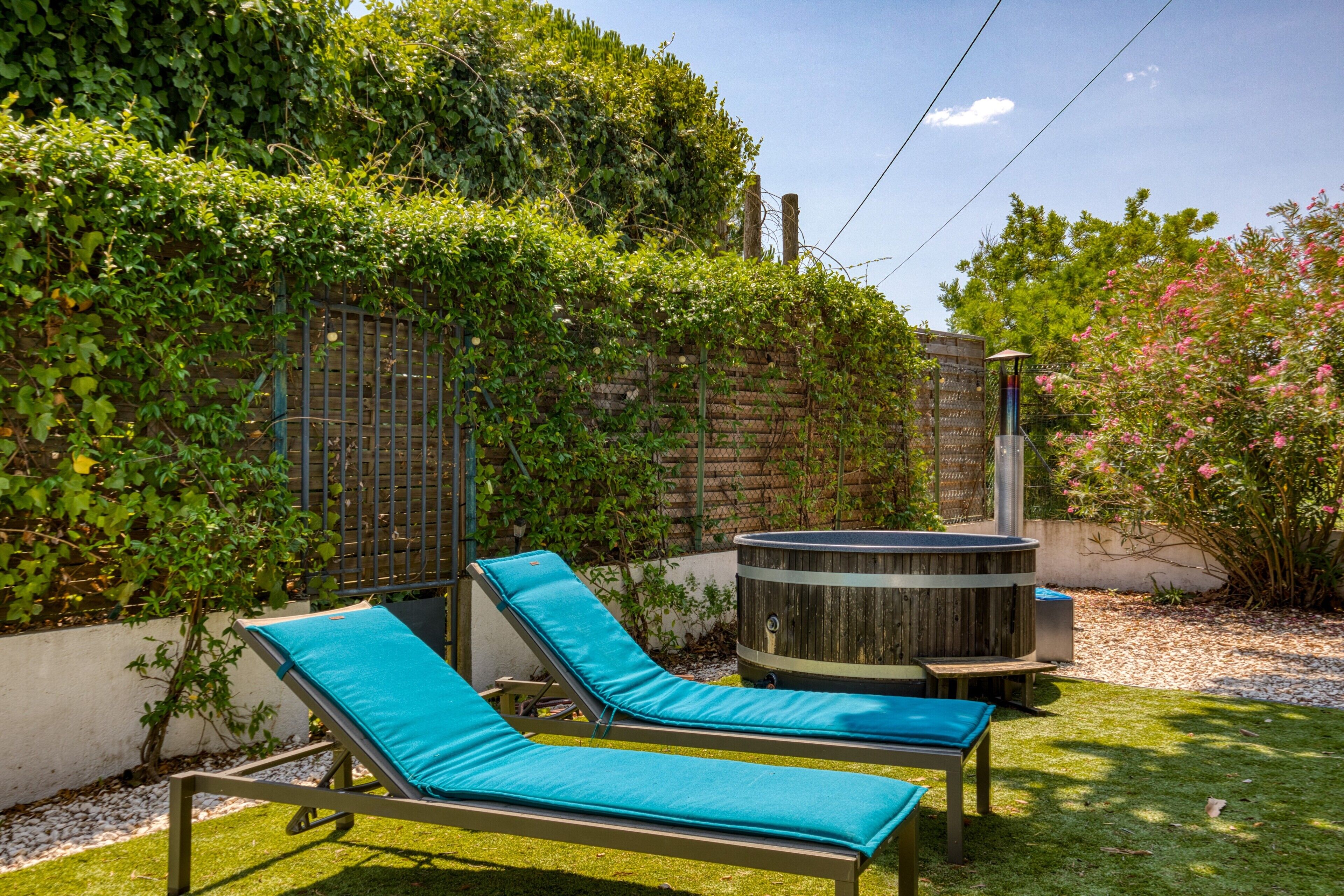 Un jardin avec deux chaises longues, un jacuzzi et un mur en briques.