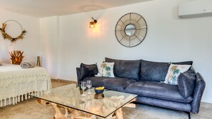 Ein Wohnzimmer mit Glastisch, dunklem Sofa, Wandspiegel und dekorativem Kranz.