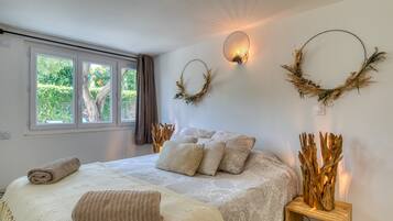 Une chambre à coucher avec un grand lit, deux appliques murales et une fenêtre avec des rideaux.