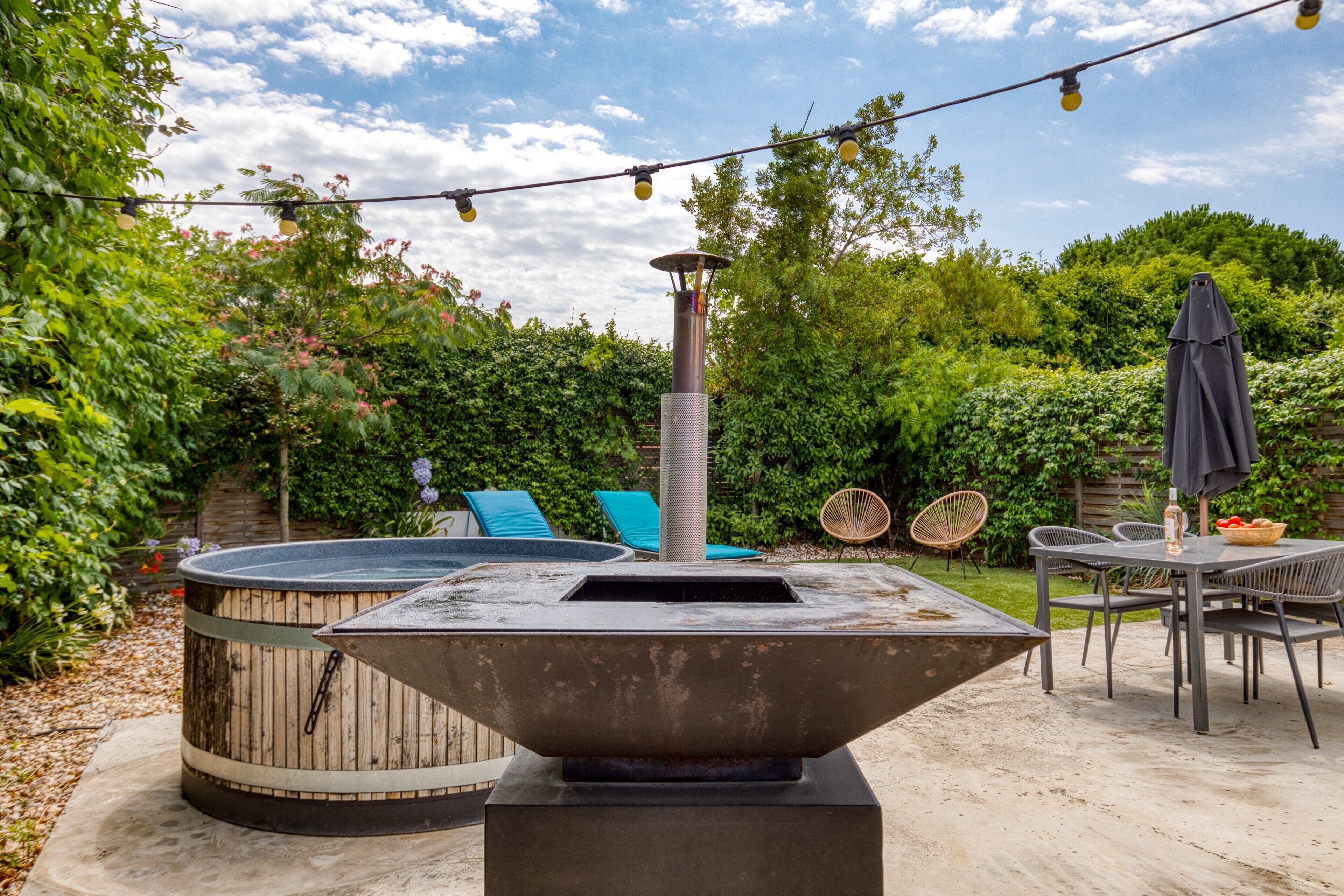 A patio with a hot tub, outdoor seating, and string lights.