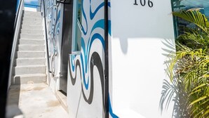 Un edificio moderno con una escalera que conduce a la entrada, el número '106' en la pared y un diseño decorativo.