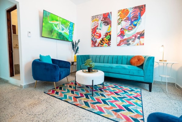 A living room with a teal sofa, a blue armchair, and a colorful rug.
