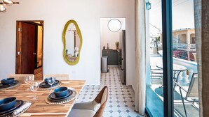 A dining area with a wooden table set for four, a mirror on the wall, and a view of a pool outside.