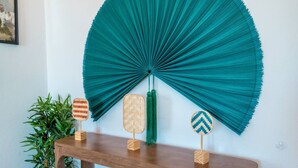 A wooden console table with three woven fans and a green plant beside it.