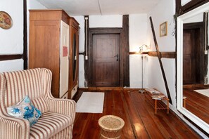 Een kamer met een houten vloer, een gestreept sofa, een kast, een deur en een spiegel.