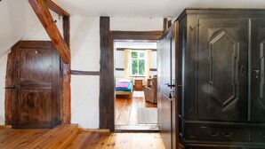 A wooden staircase leading to a bedroom with a bed, a dresser, and a window with curtains. - A room just for you (Wardow Ortsteil Polchow)