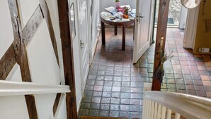 A narrow hallway with a tiled floor, a wooden door, and a table with books and a vase of flowers. - A room just for you (Wardow Ortsteil Polchow)