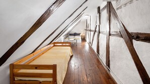 A narrow attic room with a wooden bed, a white sofa, and a small table. - Apartment 'Lemon Attic' with Shared Terrace, Shared Garden and Wi-Fi (Wardow Ortsteil Polchow)