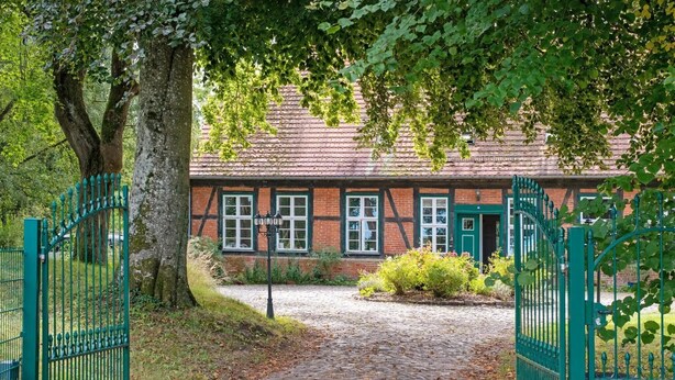 A traditional building with a brick facade, a green gate, and a cobblestone path leading to the entrance. - Apartment 'Lemon Attic' with Shared Terrace, Shared Garden and Wi-Fi (Wardow Ortsteil Polchow)