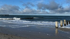 A beach with waves, a wooden pier, and cloudy skies. - Apartment 'Lemon Attic' with Shared Terrace, Shared Garden and Wi-Fi (Wardow Ortsteil Polchow)