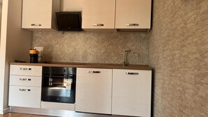 A modern kitchen with white cabinetry, a built-in oven, and a coffee maker on the countertop. - Apartment 'Olbia Comfort' with Shared Pool, Balcony and Air Conditioning (Olbia)