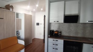 A compact living space with a sofa, kitchenette, and built-in wardrobe. - Apartment 'Olbia Comfort' with Shared Pool, Balcony and Air Conditioning (Olbia)