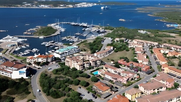 An aerial view of a coastal marina with boats, a large yacht, and residential buildings. - Apartment 'Olbia Comfort' with Shared Pool, Balcony and Air Conditioning (Olbia)