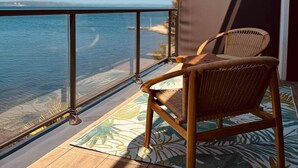 A wooden deck with a wicker chair, a glass balustrade, and a view of the sea. - Evasion room - mia casa (Saint-Mitre-les-Remparts)