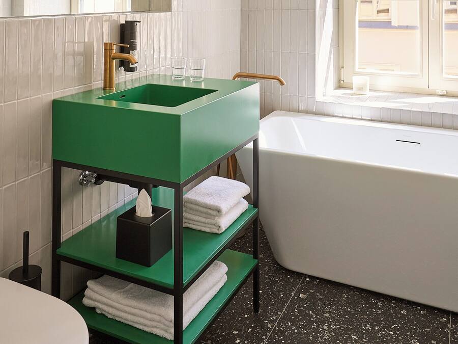 Une salle de bain avec un lavabo vert, une baignoire blanche et un grand miroir.