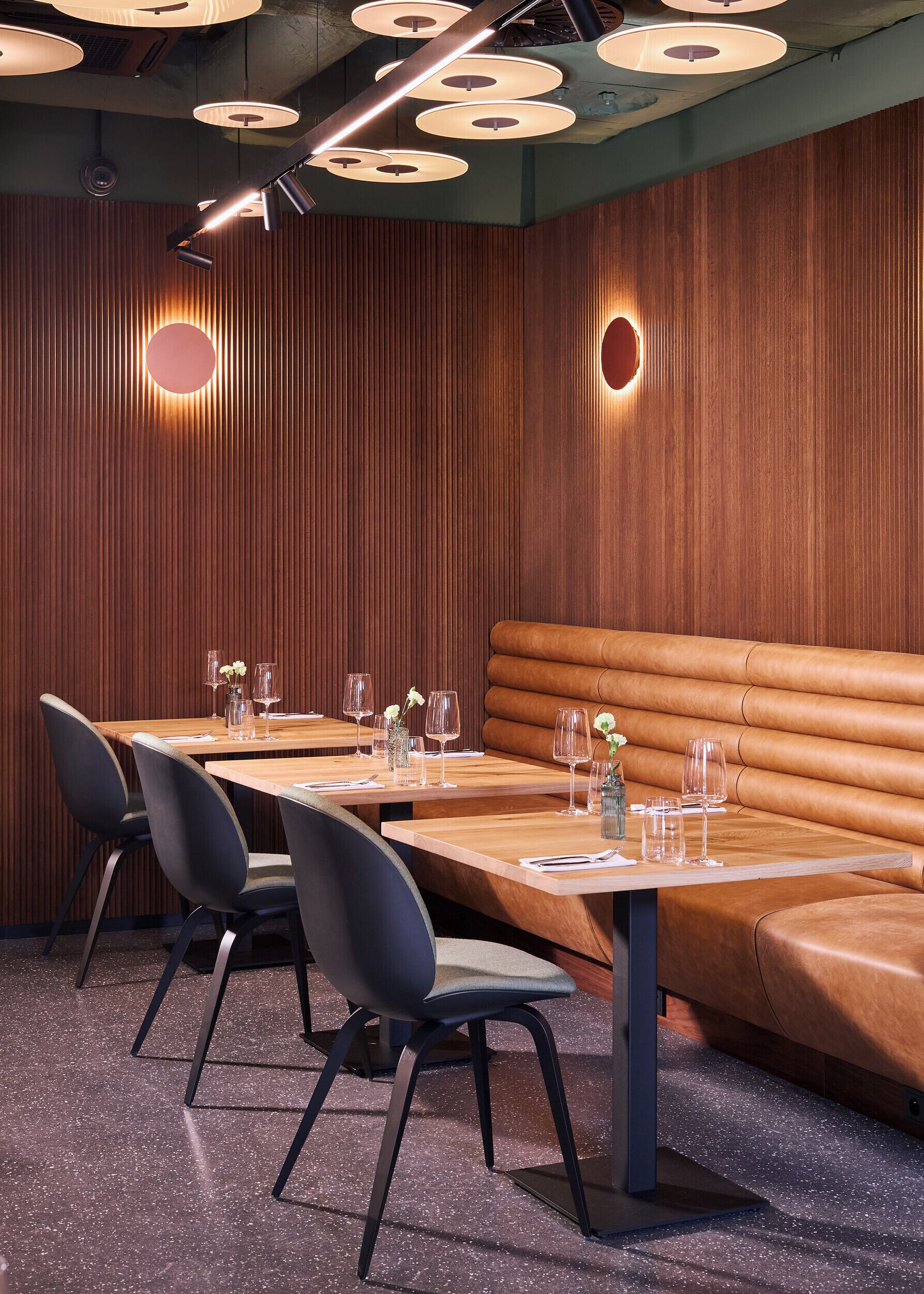 A restaurant with wooden panel walls, a long wooden table with chairs, and a leather booth.