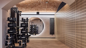 Une salle de sport équipée de matériel de musculation, dotée d’un plancher en bois et d’un plafond en briques.