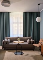 A modern living room with a sofa, a round wooden table, and a hanging light fixture.