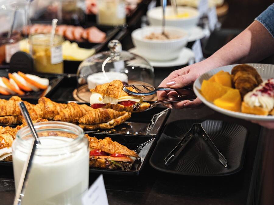 A buffet with various food items and a person serving themselves.